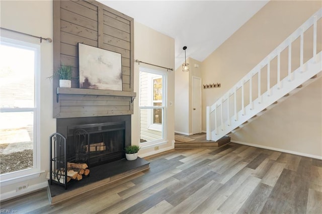 living room featuring lofted ceiling, a fireplace, and hardwood / wood-style floors