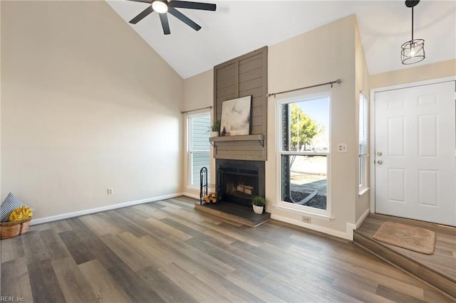 unfurnished living room with dark wood-type flooring, a fireplace, high vaulted ceiling, and ceiling fan