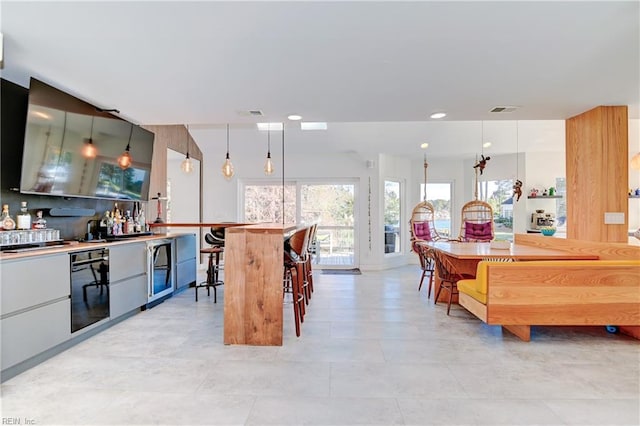 kitchen featuring wall oven, decorative light fixtures, white cabinets, and a kitchen bar