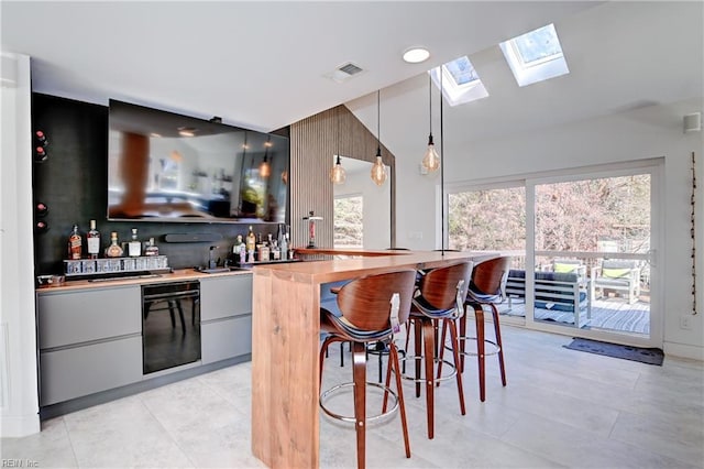 bar with light tile patterned flooring, decorative light fixtures, and a skylight