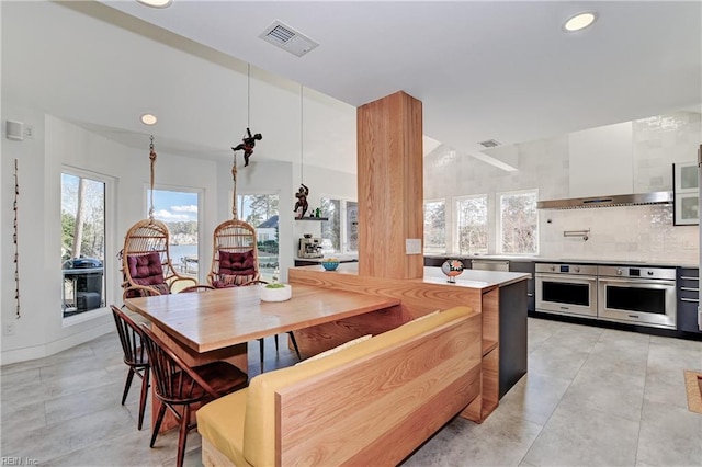 kitchen with tasteful backsplash, pendant lighting, stainless steel appliances, and wall chimney exhaust hood