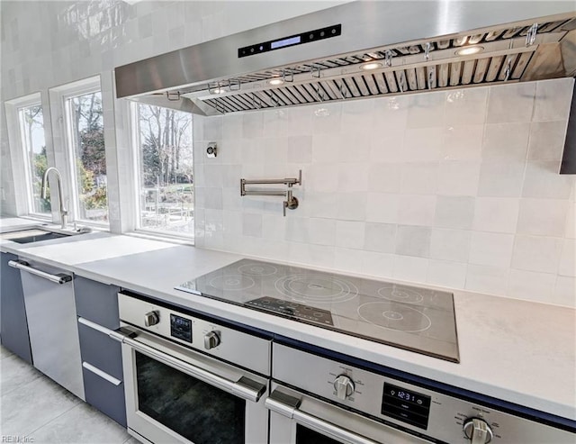 kitchen featuring sink, black electric stovetop, decorative backsplash, exhaust hood, and stainless steel oven