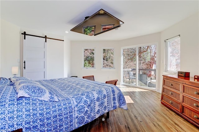 bedroom with a barn door, light hardwood / wood-style flooring, and access to outside