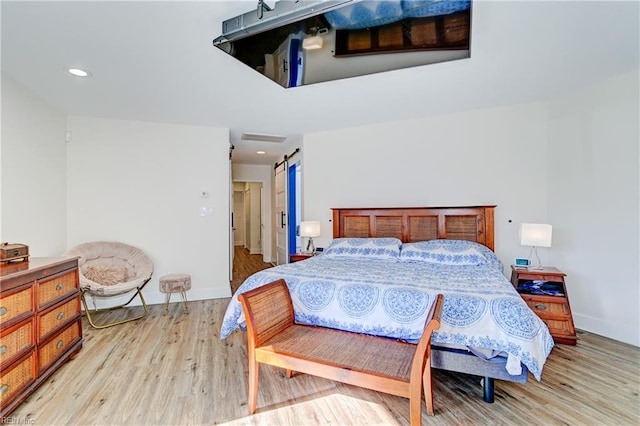 bedroom featuring a barn door and light wood-type flooring