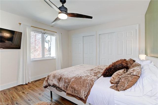 bedroom featuring multiple closets, ceiling fan, and light wood-type flooring