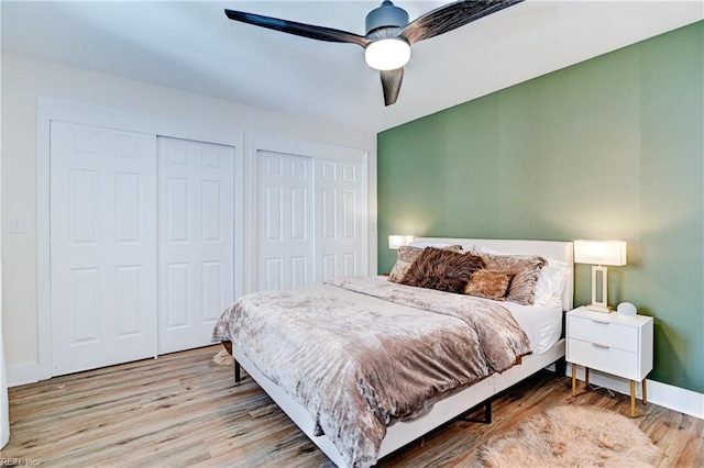 bedroom with multiple closets, ceiling fan, and light wood-type flooring