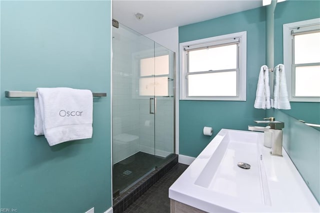 bathroom with tile patterned floors, plenty of natural light, a shower with door, and vanity