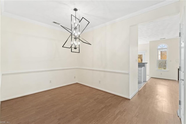 unfurnished dining area with ornamental molding, wood-type flooring, and a notable chandelier