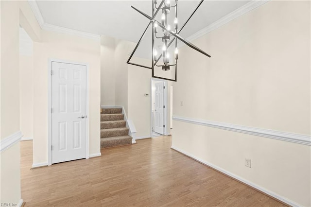 unfurnished dining area featuring crown molding, a chandelier, and light hardwood / wood-style floors