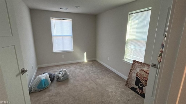 unfurnished room featuring plenty of natural light and light carpet