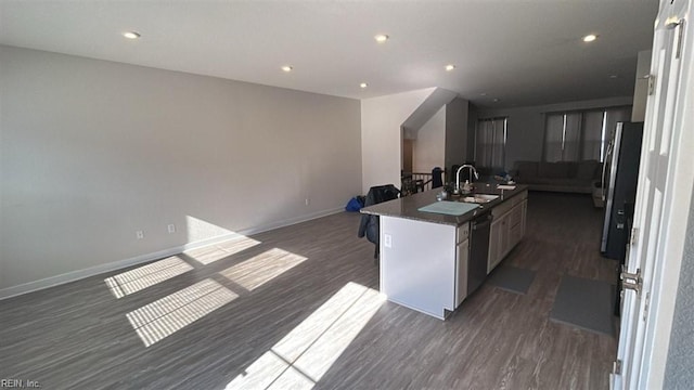 kitchen with sink, stainless steel appliances, dark hardwood / wood-style flooring, and a kitchen island with sink