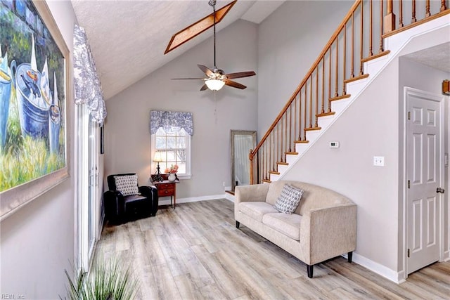 living room with ceiling fan, high vaulted ceiling, and light hardwood / wood-style flooring