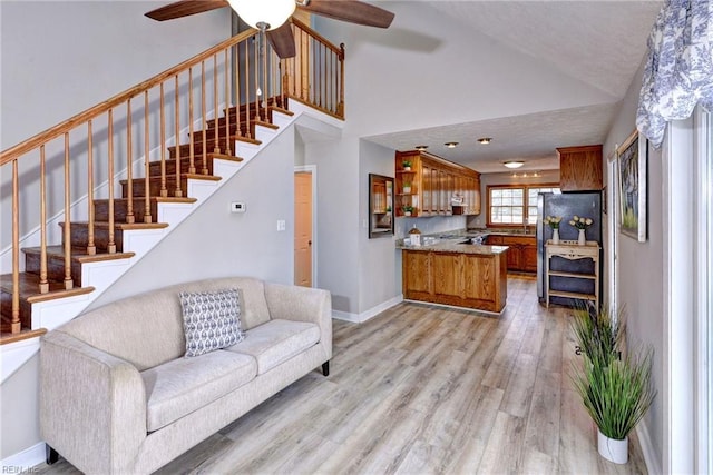 living room with ceiling fan, high vaulted ceiling, and light wood-type flooring