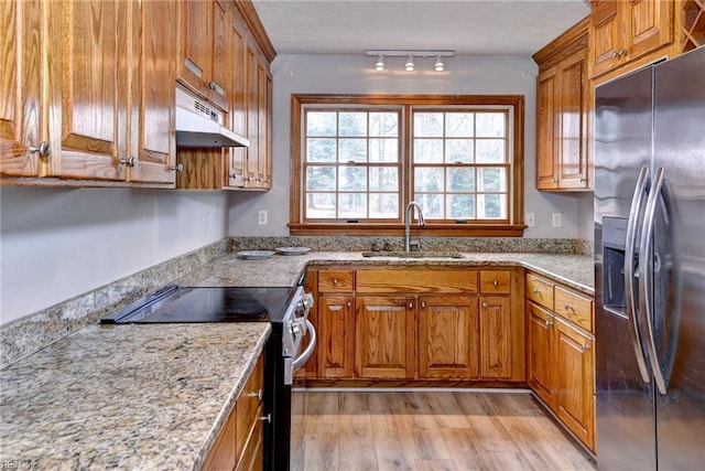 kitchen featuring light stone counters, appliances with stainless steel finishes, light hardwood / wood-style floors, and sink