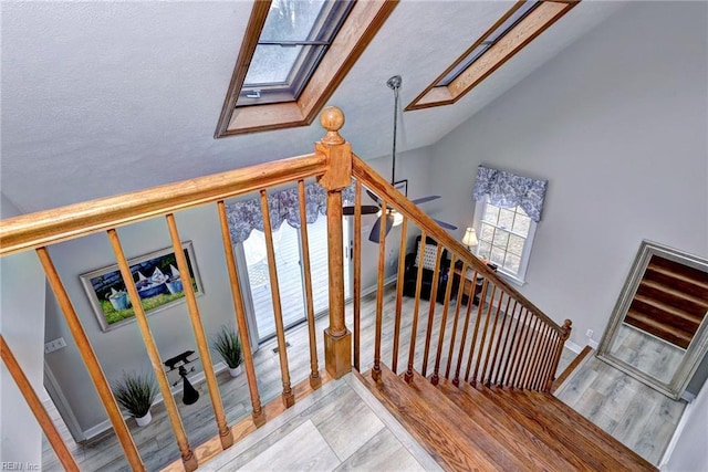 stairs featuring vaulted ceiling with skylight and hardwood / wood-style floors