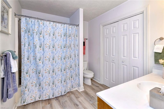 bathroom with vanity, toilet, wood-type flooring, and a textured ceiling