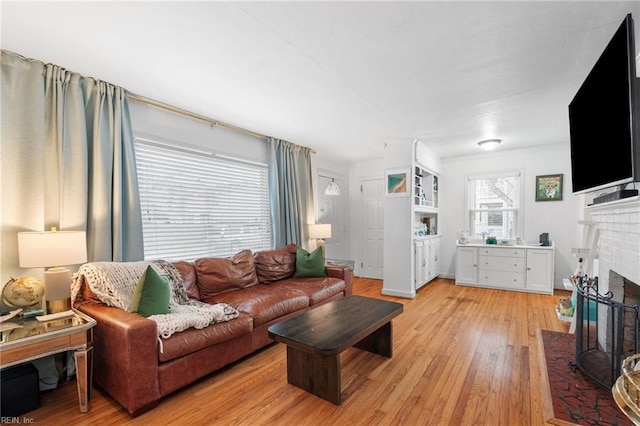 living room featuring a brick fireplace and light hardwood / wood-style floors