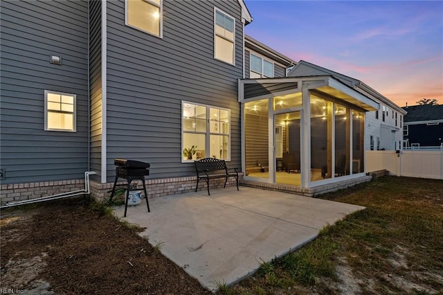 back house at dusk featuring a patio area and a sunroom