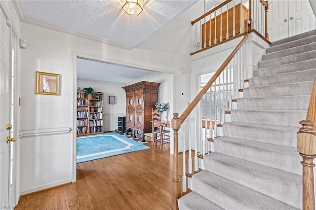 foyer entrance featuring crown molding, hardwood / wood-style floors, and a textured ceiling