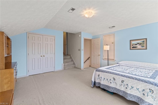 carpeted bedroom featuring lofted ceiling, a textured ceiling, and a closet