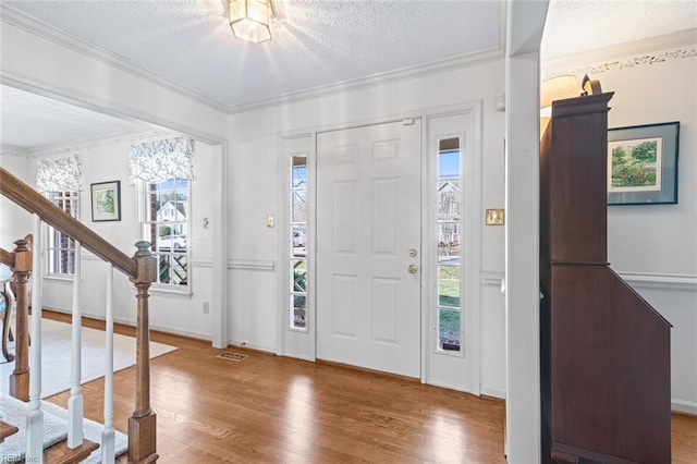 entryway featuring crown molding, plenty of natural light, hardwood / wood-style floors, and a textured ceiling