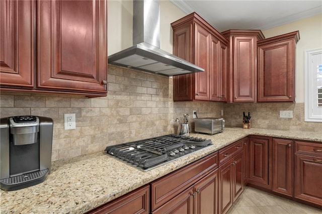 kitchen featuring stainless steel gas cooktop, decorative backsplash, light stone counters, and wall chimney exhaust hood