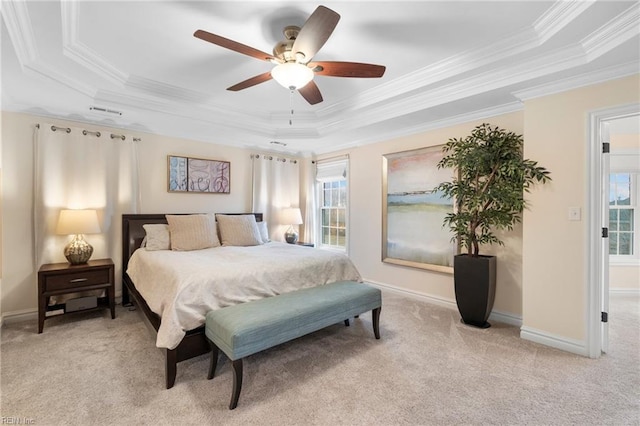 carpeted bedroom featuring multiple windows, ornamental molding, and a tray ceiling