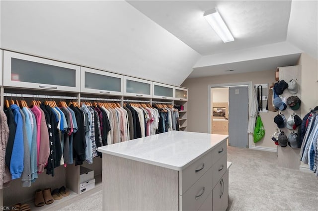 walk in closet with light colored carpet and lofted ceiling