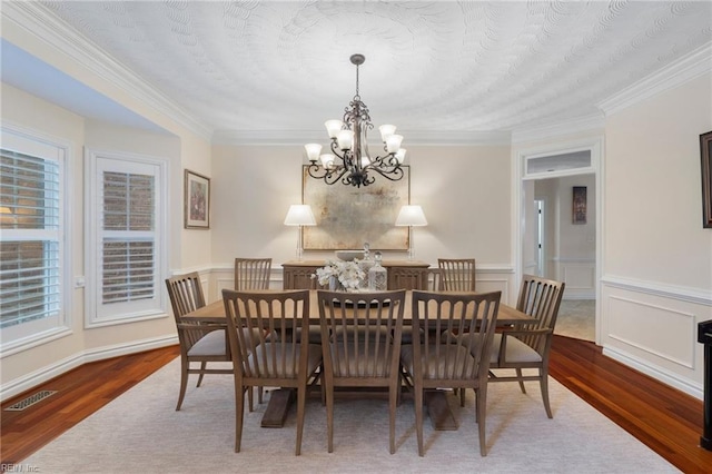 dining room featuring an inviting chandelier, wood-type flooring, a wealth of natural light, and crown molding