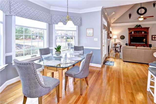 dining space with ceiling fan with notable chandelier, vaulted ceiling, ornamental molding, and light wood-type flooring