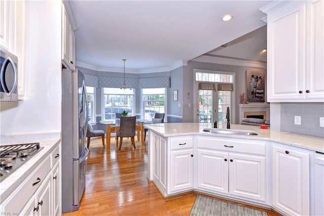 kitchen featuring decorative light fixtures, kitchen peninsula, sink, and white cabinets