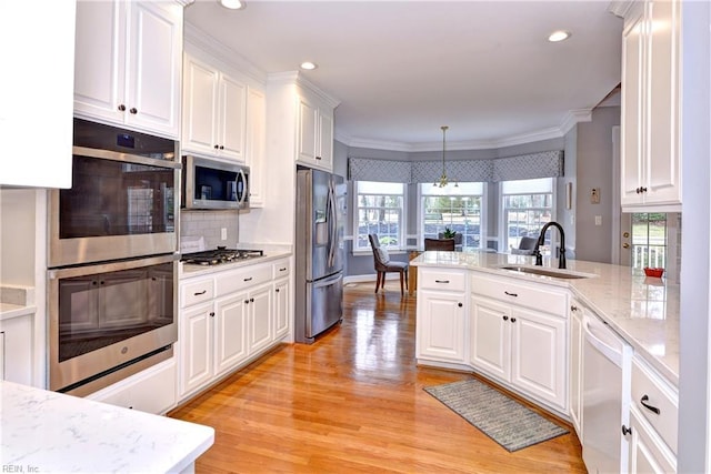 kitchen featuring pendant lighting, sink, crown molding, appliances with stainless steel finishes, and white cabinets