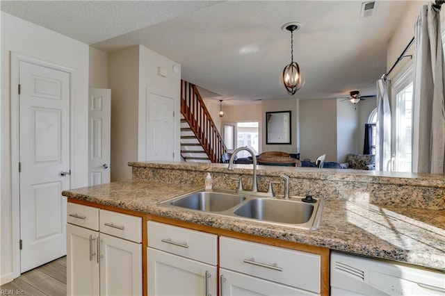 kitchen featuring sink, white cabinetry, light hardwood / wood-style flooring, white dishwasher, and pendant lighting