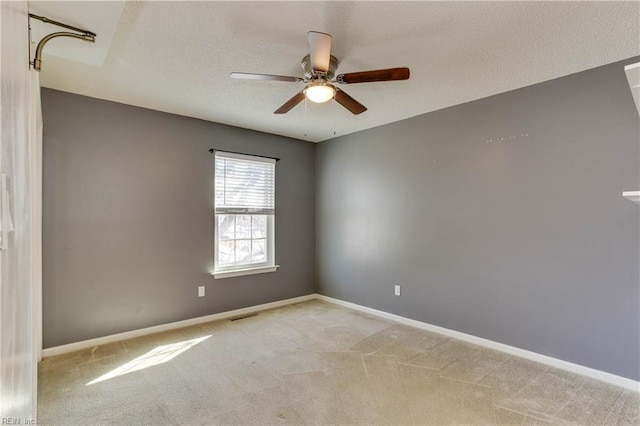 empty room featuring light colored carpet, a textured ceiling, and ceiling fan