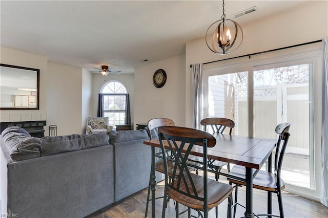 dining space with ceiling fan with notable chandelier and hardwood / wood-style floors