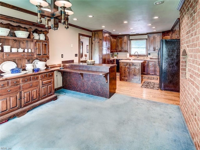 kitchen featuring crown molding, a center island, black refrigerator, a notable chandelier, and light hardwood / wood-style floors