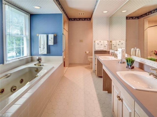 bathroom featuring a relaxing tiled tub, tile patterned floors, vanity, and toilet