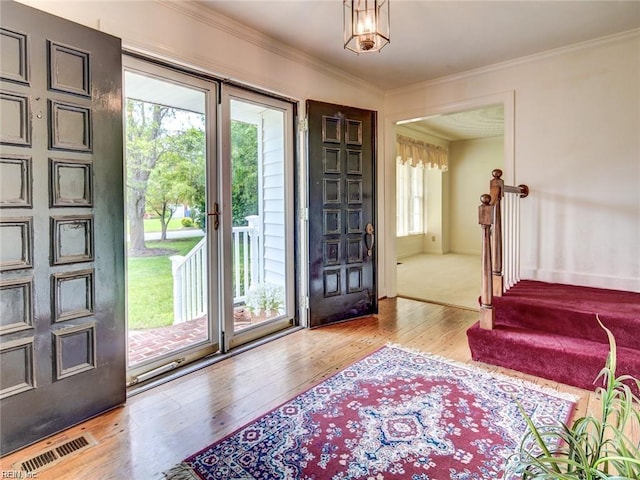 foyer featuring crown molding, a healthy amount of sunlight, and light wood-type flooring