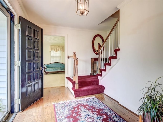 entrance foyer featuring crown molding and light hardwood / wood-style floors