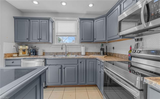 kitchen featuring sink, light tile patterned floors, gray cabinetry, backsplash, and stainless steel appliances