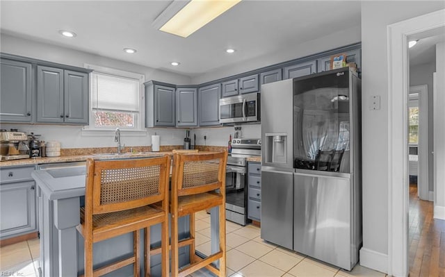 kitchen featuring a kitchen island, sink, gray cabinets, and appliances with stainless steel finishes