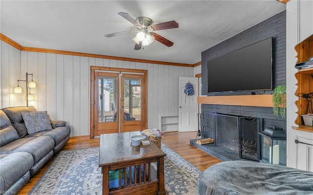 living room with crown molding, hardwood / wood-style floors, a fireplace, and ceiling fan