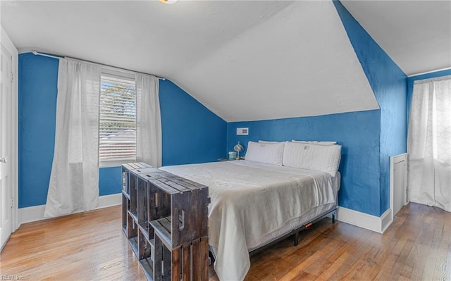 bedroom with wood-type flooring and vaulted ceiling