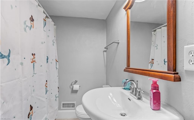 bathroom featuring sink, toilet, and a shower with shower curtain