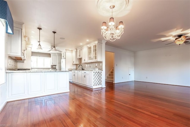 kitchen with decorative light fixtures, ceiling fan with notable chandelier, and white cabinets