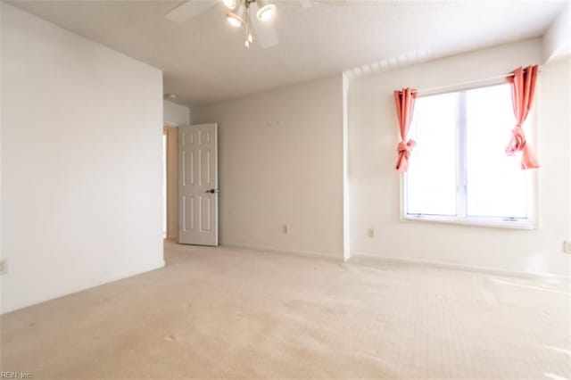 spare room featuring light colored carpet and ceiling fan