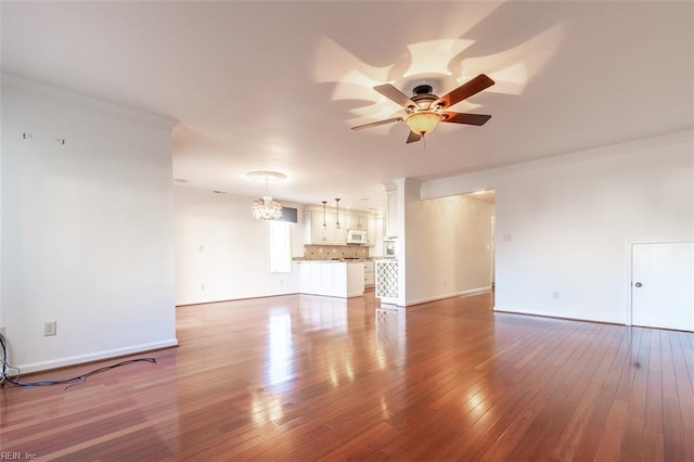 unfurnished living room featuring hardwood / wood-style flooring, crown molding, and ceiling fan with notable chandelier