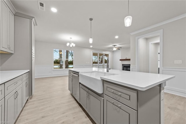 kitchen with stainless steel dishwasher, decorative light fixtures, a kitchen island with sink, and gray cabinetry