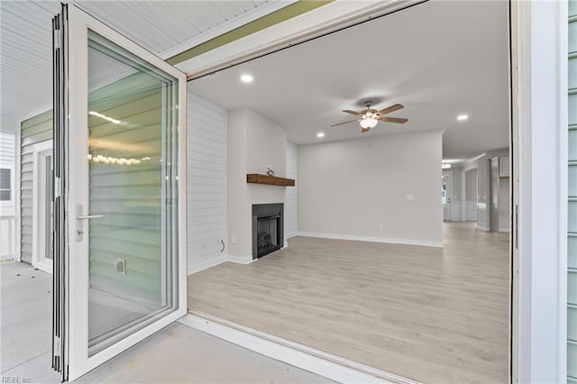 unfurnished living room featuring a large fireplace, ceiling fan, and light hardwood / wood-style floors