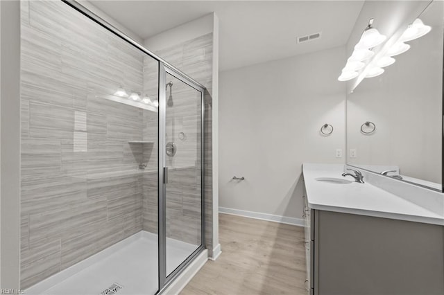 bathroom with walk in shower, vanity, and hardwood / wood-style floors